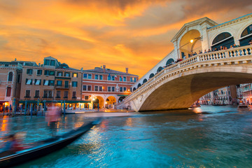 Fototapeta na wymiar Bright charming landscape with gondola and Rialto Bridge at sunset in Venice, Italy, Europe