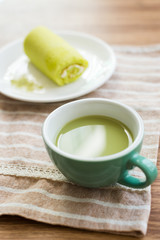 Roll cake with green tea on wooden table