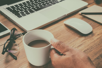 cup of coffee on old wooden desk. Simple workspace or coffee break in morning/ selective focus