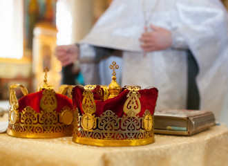 Fototapeta na wymiar Ceremony of the wedding in the Russian Orthodox Church. The crowns lie near the bible close up.