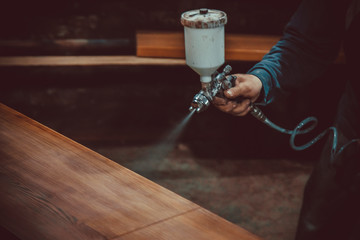 Master painter in a factory - industrial painting  wood with spray gun. Soft focus. Shallow DOF.