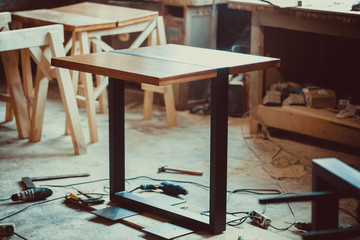 Beautiful finished table with natural iron and wood stands on the in a carpenter's shop. Soft focus. Shallow DOF. © Ievgenii Meyer