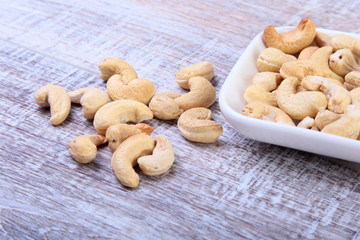 nuts cashews in white bowl on wooden background. Selective focus.