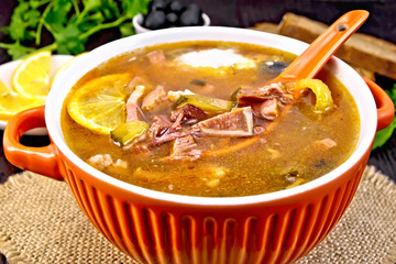Solyanka with spoon in bowl on board