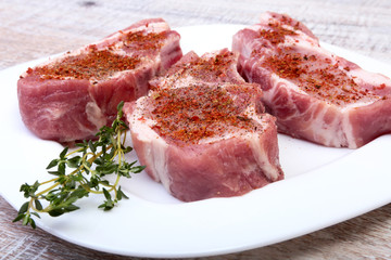 Raw pork chops, spices and rosemary on cutting board. Ready for cooking.