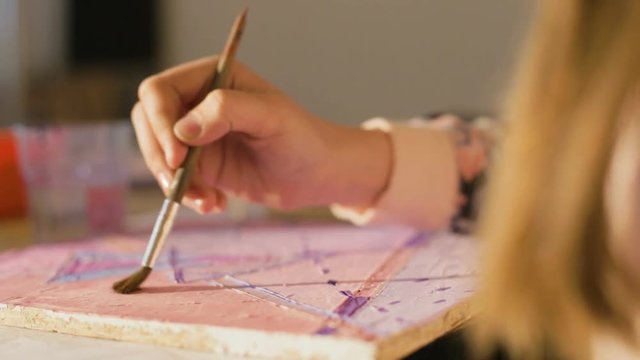Close up hands of a child holding a brush and paints