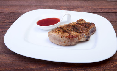grilled pork chop with Cranberry sauce on plate on wooden board