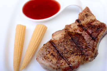 grilled pork chop with Cranberry sauce and Mini Corn cob preserved on plate on wooden board