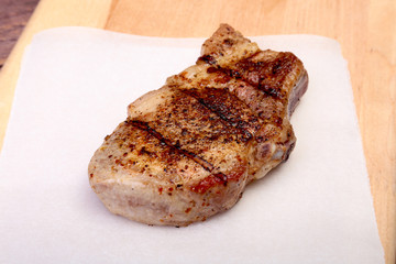 grilled pork chop on plate on wooden board