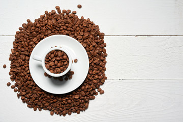 Coffee love concept. Top view of coffee cup full of coffee beans on white rustic wooden background