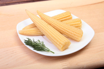 Mini Corn cob preserved on plate on wooden board.