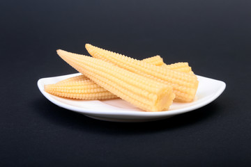 Mini Corn cob preserved on plate on wooden board.