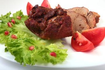 Steak of grilled meat with tomato, lettuce and beans pomegranate on white plate.