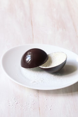 Coconut - Chocolate Decoration, on white plate, on white wooden background.