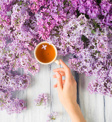 Woman's hand takes a cup on a table with flower