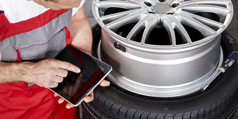 Mechanic fits tyre pressure monitoring system with tablet 