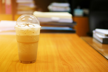 Mocha frappe in a clear plastic glass on office desk with light rays as selective focus