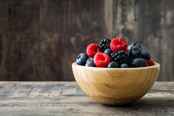 Healthy berries in wooden bowl on wooden table
