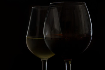 Wine glasses on black - two glasses of red and white wine close up