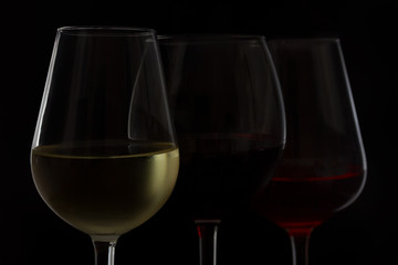 Wine glasses on black - tree glasses of red, rose and white wine close up