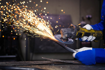 Grinding a piece of metal pipe and producing sparks. - obrazy, fototapety, plakaty
