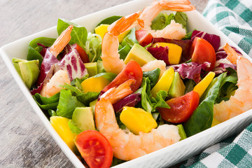 Shrimps salad with mango and avocado on wooden table
