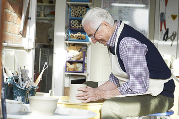 Senior Man Working At Pottery Wheel In Studio