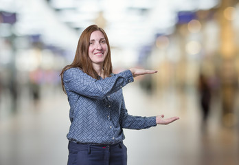 Pretty business woman presenting something over blur background