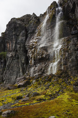 Water jet fall along wet rock to mossy stones, Norway