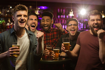Four happy men holding beer mugs and gesturing