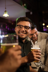 Smiling man having beer with his friends in a pub