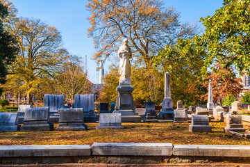 Group of tombstones and sculpture of Virgin Mary on the Oakland Cemetery in sunny autumn day, Atlanta, USA