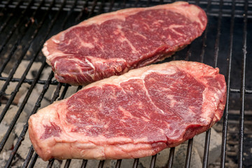 raw beef steaks on a grill