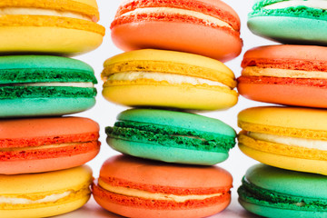 Multicolored macaroons (orange, yellow and green) close.