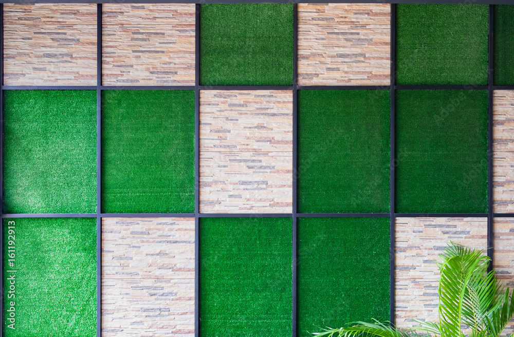 Wall mural wall of stone and artificial grass background with metal frame and palm tree.