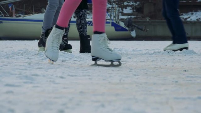 A girl in pink pants ice skates on a crowded frozen river, a puck travels to