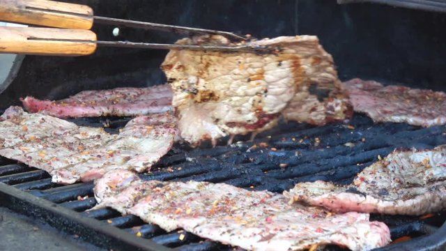 Man's hands cooking meat on grill