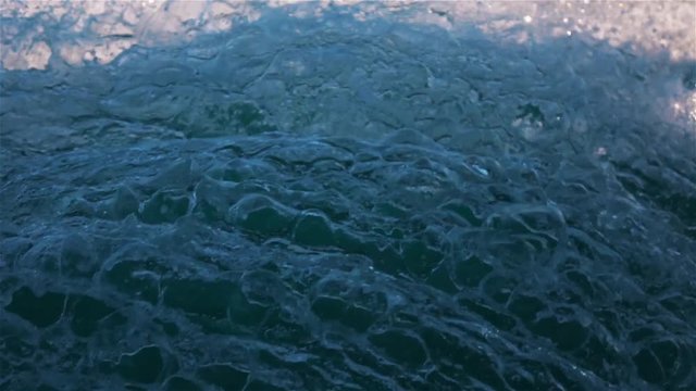 Super slow motion of water flow speed boat foam with spraying and splashing. Ocean teal and orange wide shot.