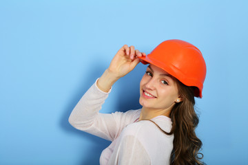 Positive smiling young woman in helmet for repair on blue background