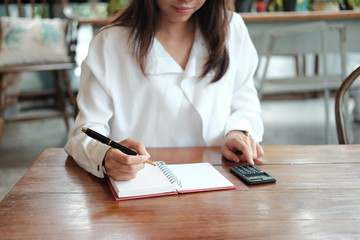 young student woman holding pen for writing on notebook paper and using calculator for calculate. image for business,education,people and portrait concept