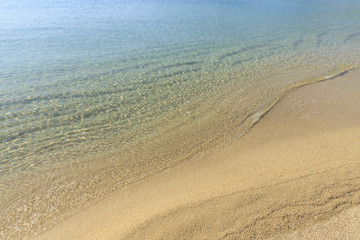 Fototapeta na wymiar Soft sea wave on sandy beach, Beautiful Greek beach with fine sand, Close up photo of sandy beach with soft wave in motion