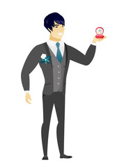 Young groom holding wedding ring in box.