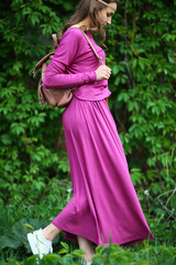 Stylish girl walking on street, park, walking in purple dress, on green wall, leaf background, walker