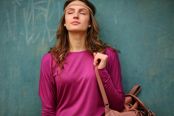 Resting enjoy woman standing upper half, closed eyes, blue urban wall, street lifestyle