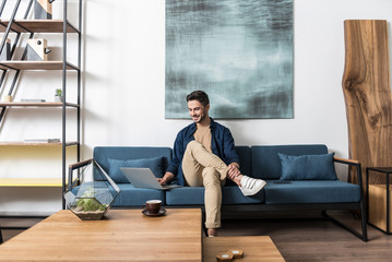Joyful bearded man working indoors at his living room