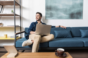 Happy youthful guy working at home via computer
