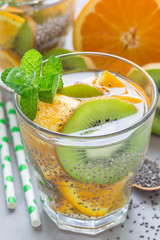 Healthy detox chia seed drink with kiwi, orange and mint in glass, vertical, closeup