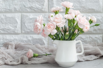 Small tender pink carnation flowers in vase on gray concrete with copy space, mother's day greeting card background, horizontal