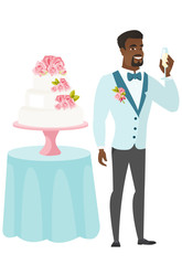 Groom standing near cake with glass of champagne.