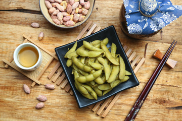boiled edamame in black plate with rice wine and peanut